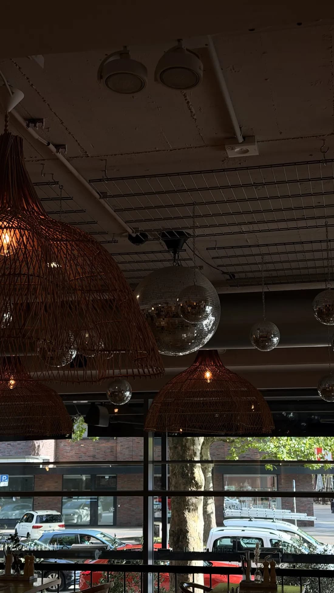 Disco balls between rattan lamps under the ceiling, the window to the street behind