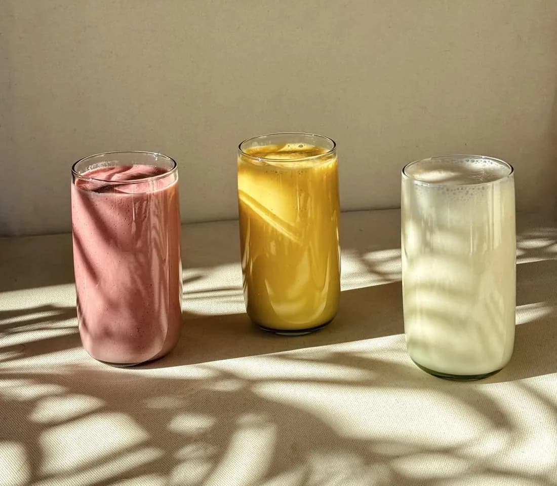 Three milkshakes, raspberry, mango and vanilla, in the sunlight