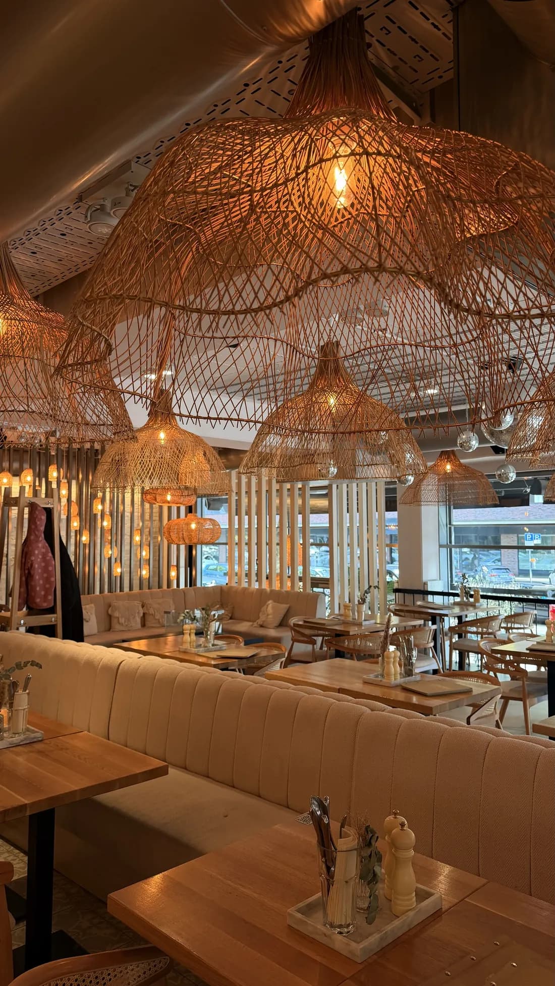 Large woven rattan lamps above the long upholstered bench at Café Bohoo