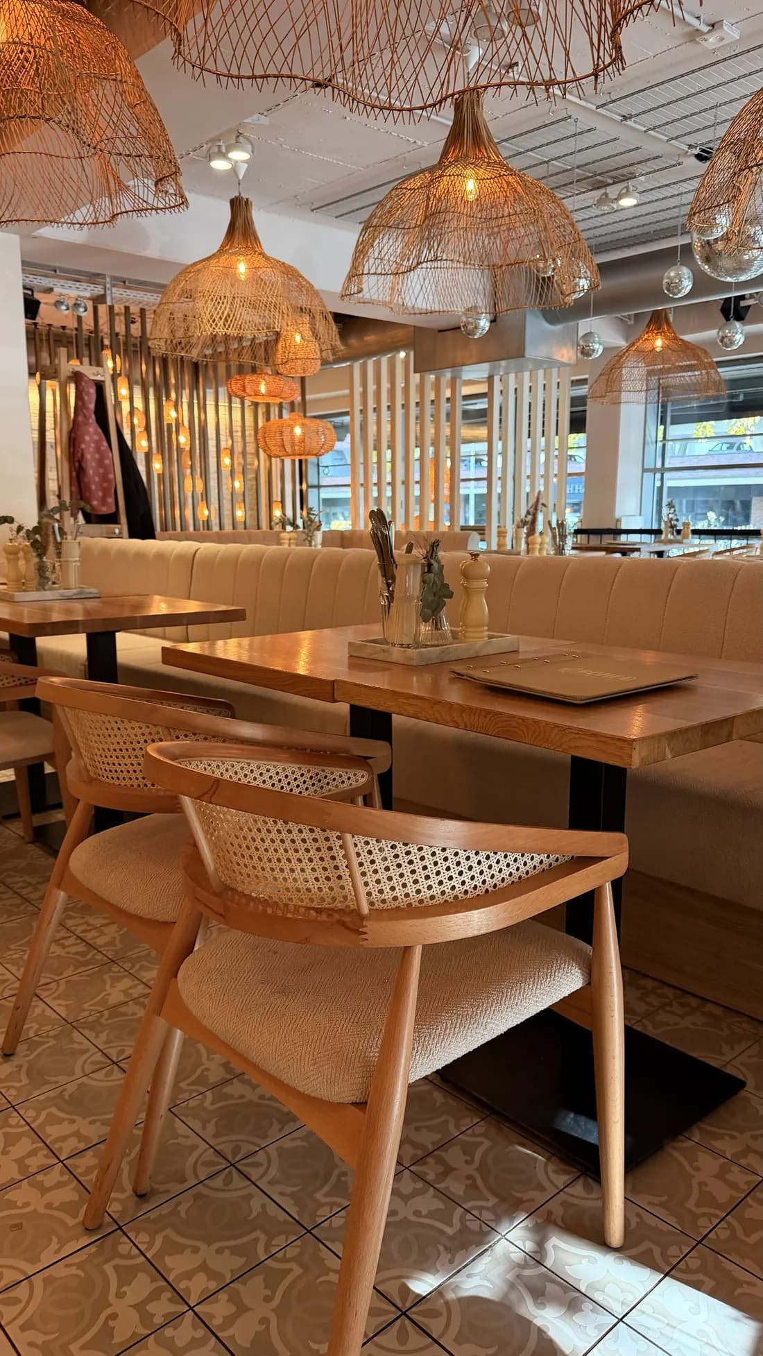 Wooden chair with Viennese cane at a table in front of the bench, rattan lamps above